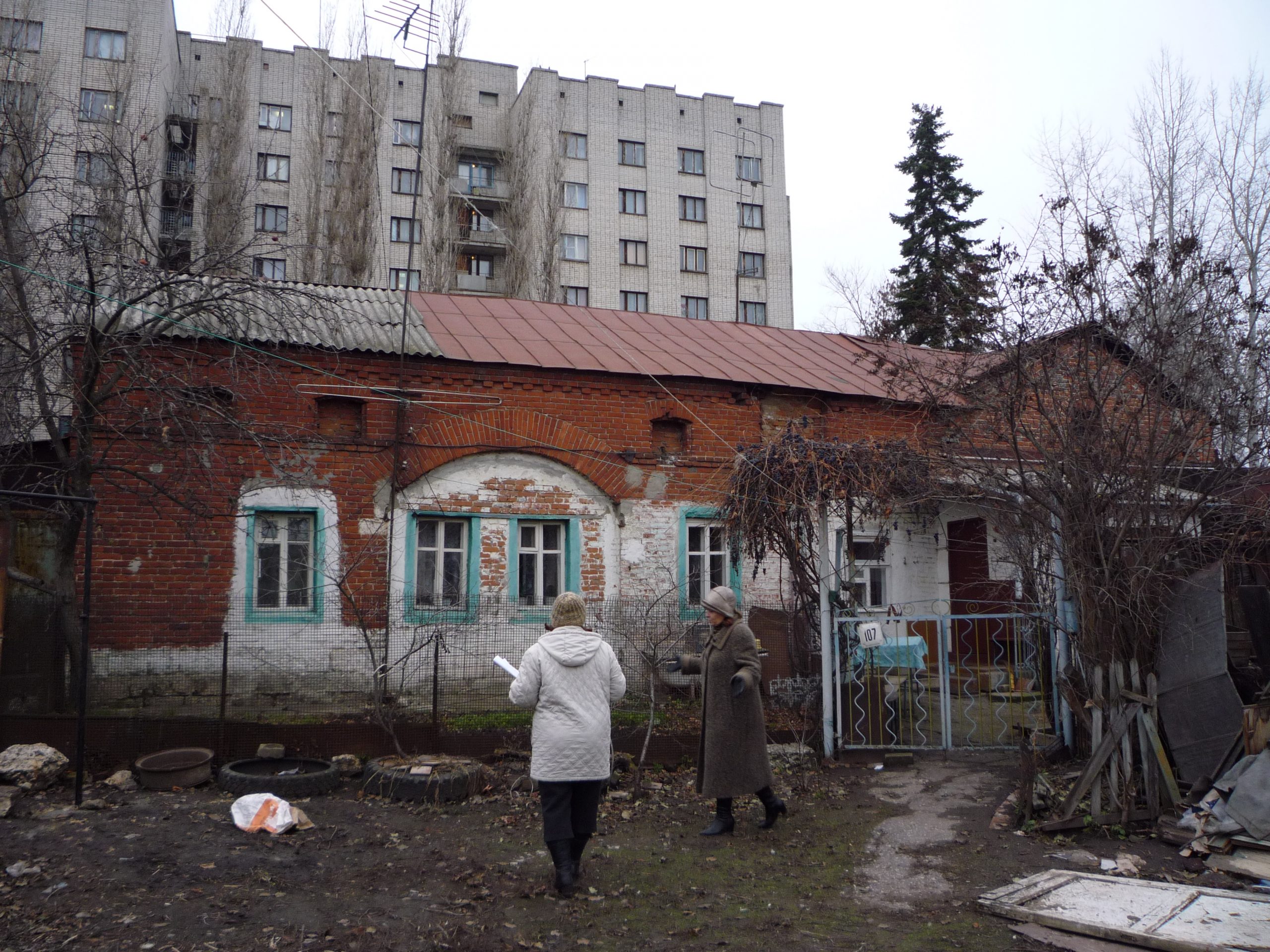Кирпичная хозяйственная постройка во дворе усадьбы на Советской, 107: широкая арка заложена стеной с окнами.